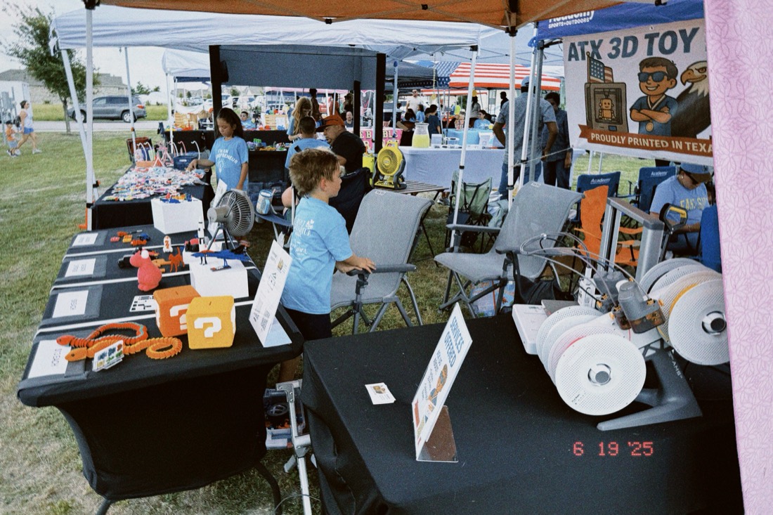 Joseph's market booth with his 3D printers running on the table